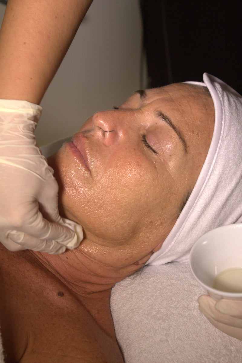 Esteticista valorando la piel del rostro de una clienta durante un tratamiento facial en Glo&Beauty Badalona