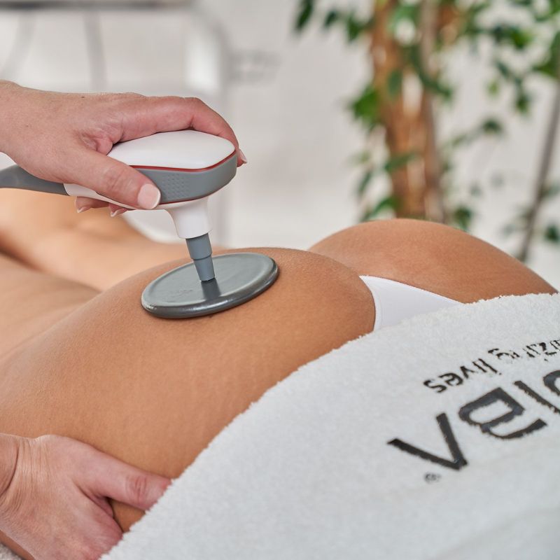 Mujer en una sesión de masaje con un dispositivo Indiba, experimentando alivio y bienestar en su cuerpo.